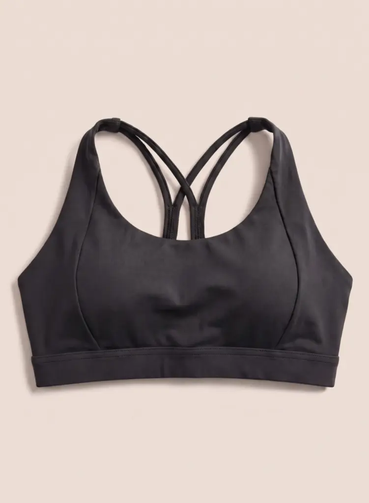Vauxelle black sports bra front flat lay on warm cream background